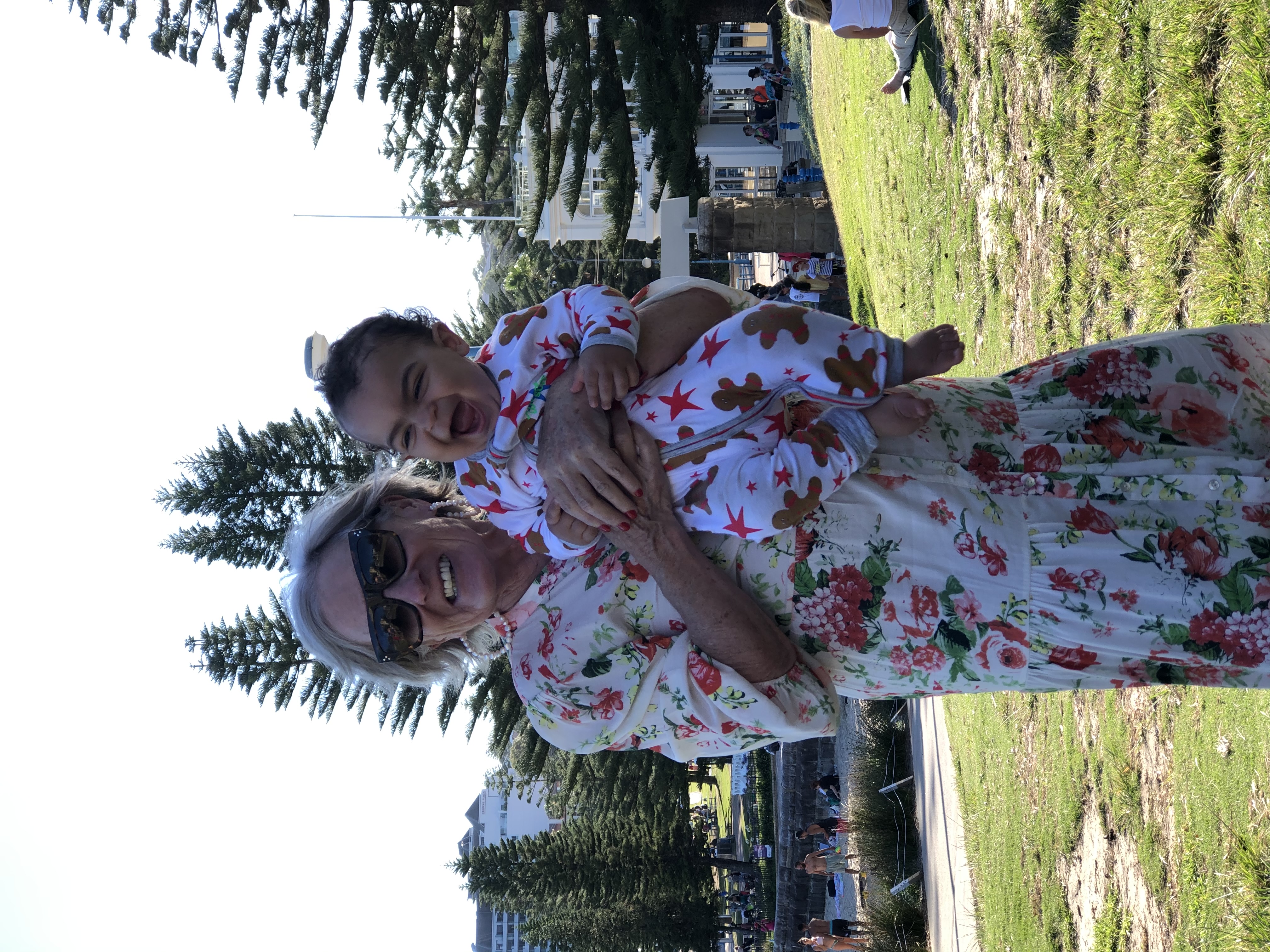 Nanna holding laughing baby girl outdoors