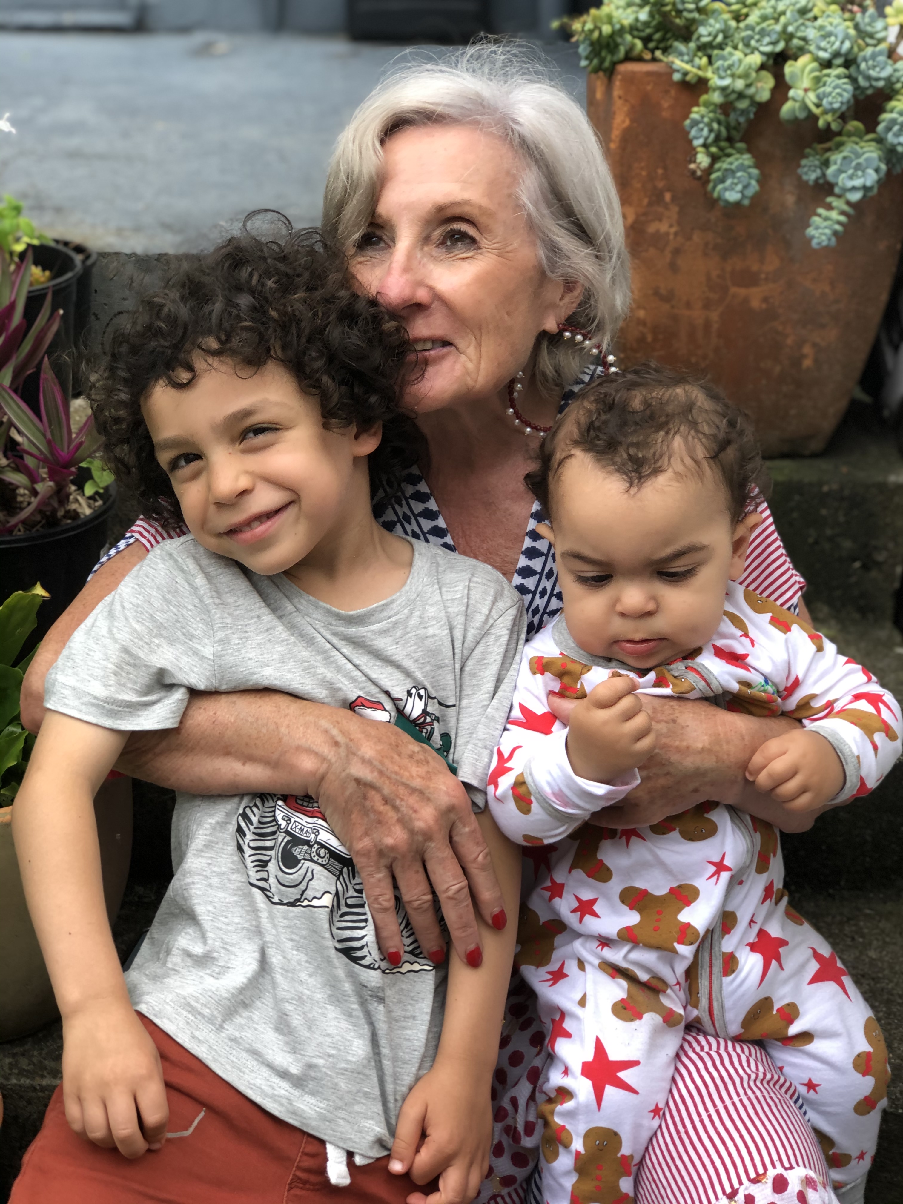 Nanna cuddling two young boys in a garden